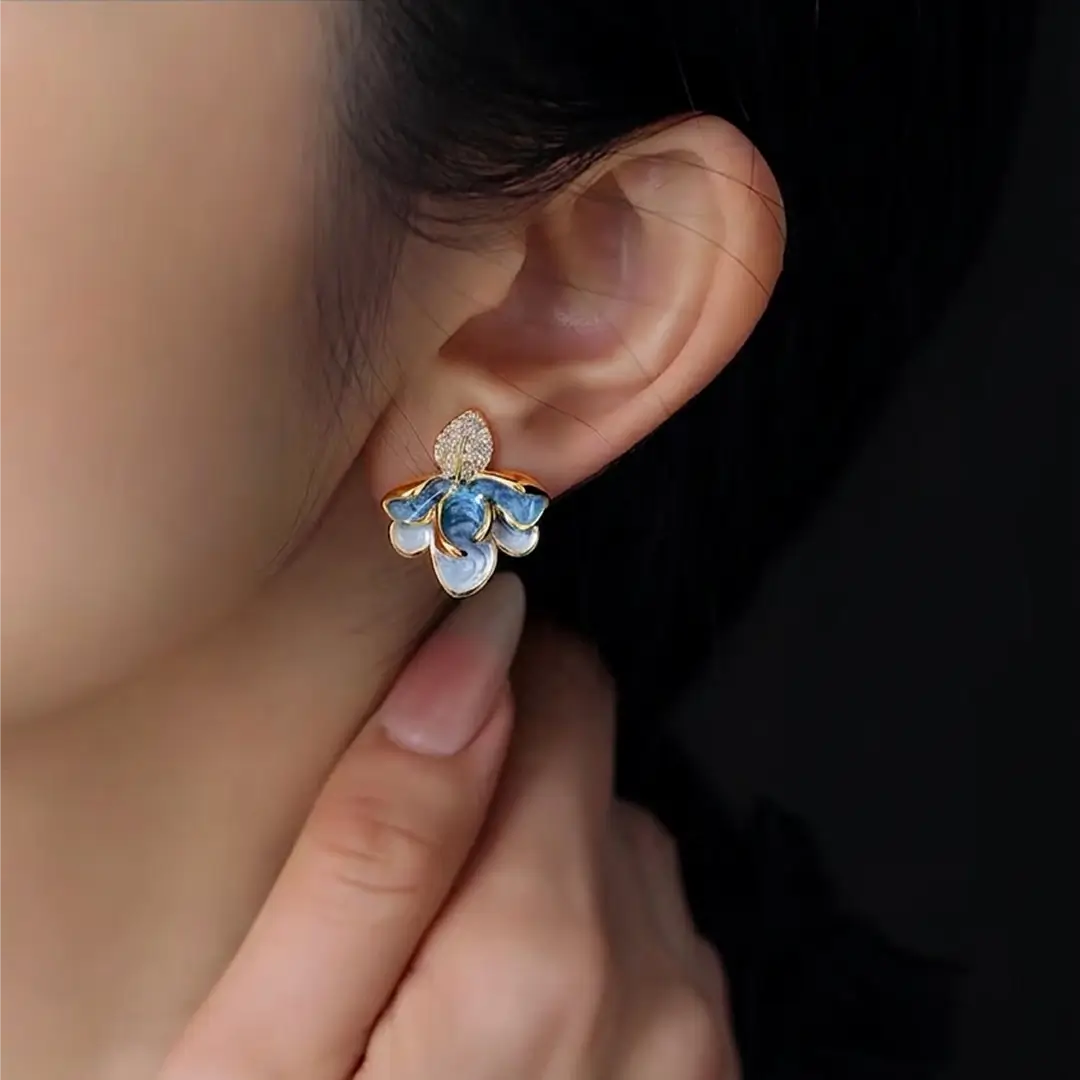 Close-up of an ear wearing the Aiko Tanaka Soka blue enamel flower stud with gold crystal leaves
