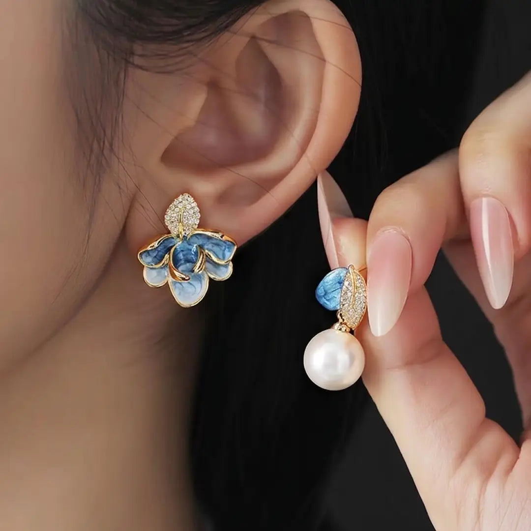 Woman holding a pearl near her ear while wearing the Aiko Tanaka Soka blue enamel flower earring with pearl