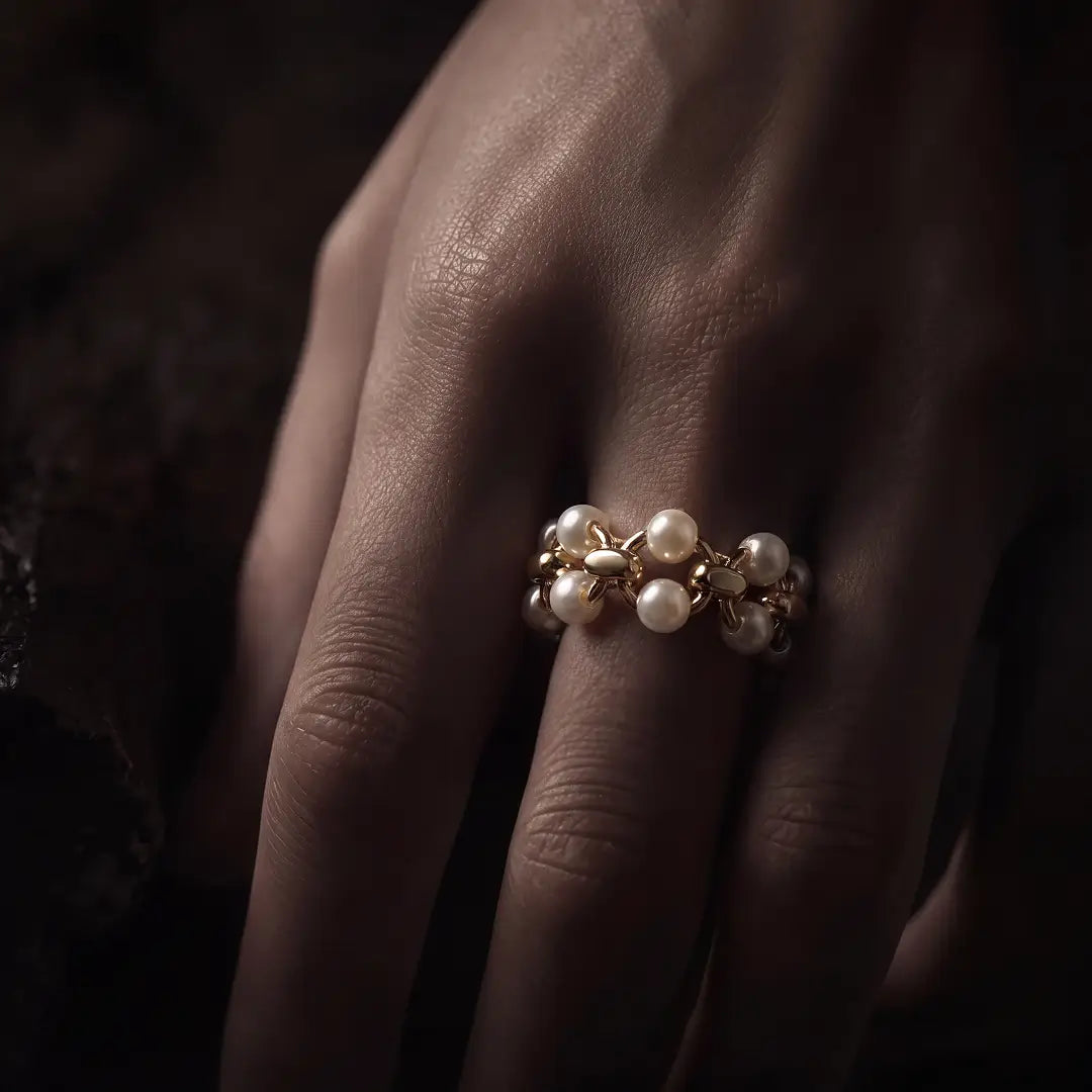 Aiko Tanaka Enrei ring, a gold pearl and flower cluster ring, worn on the hand against a dark background