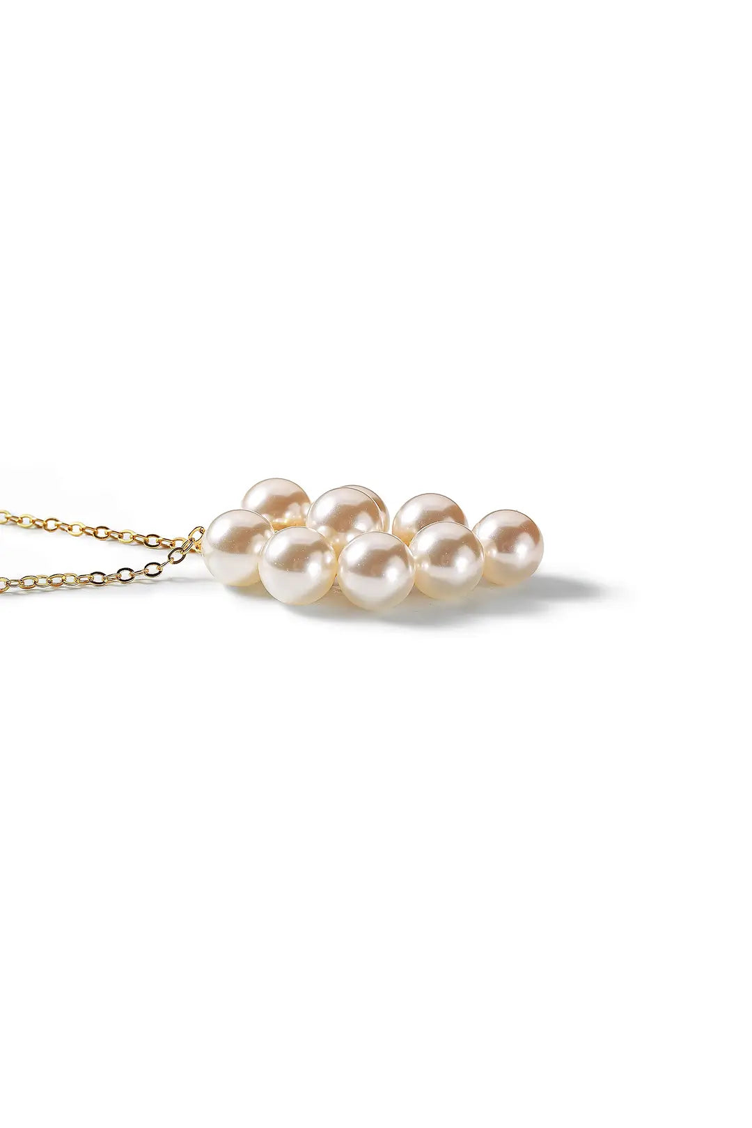 Aiko Tanaka Yorika necklace lying flat, a gold chain with a grape-like cluster of white pearls, on white
