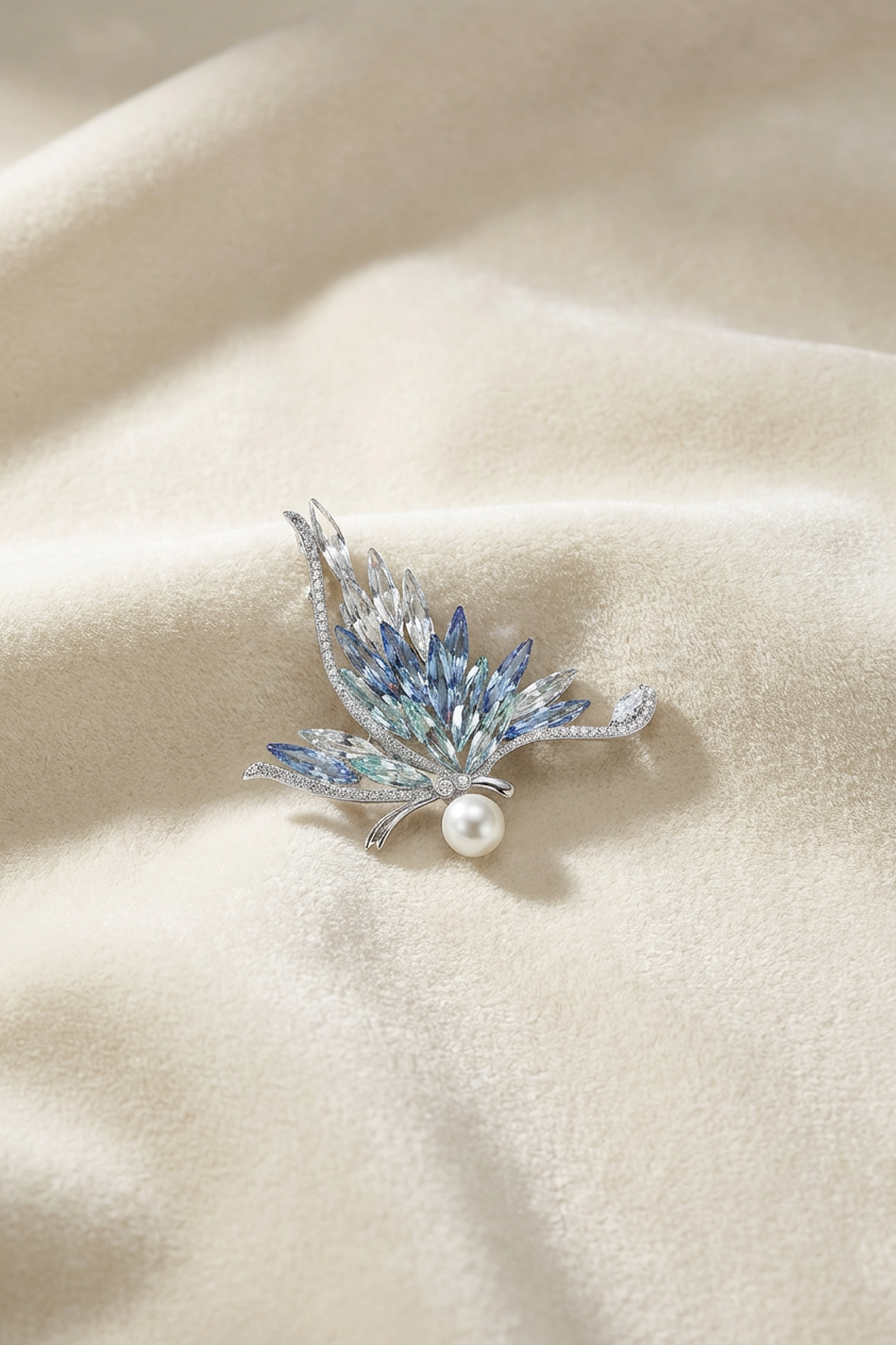 Aiko Tanaka Ao no Senko brooch with blue marquise crystals and a white pearl, resting on soft cream fabric