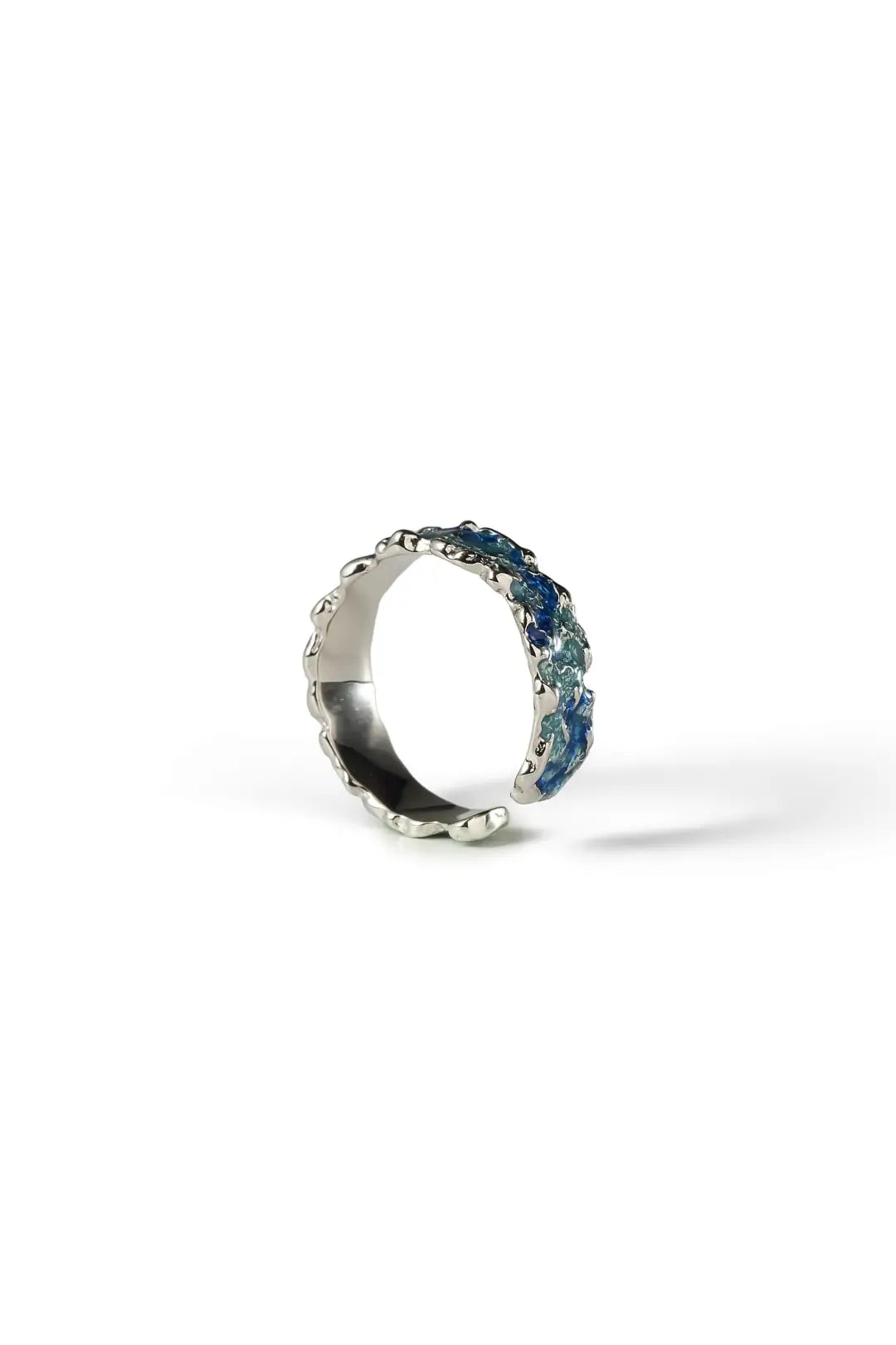 Aiko Tanaka Awanami ring, a silver band with blue enamel ocean waves set with small stones, on a white background
