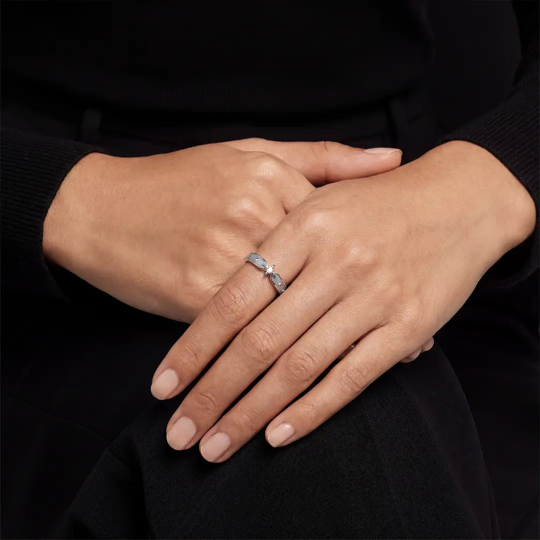 Hands crossed over a black top wearing the Aiko Tanaka Hoshikage open silver ring with a small star