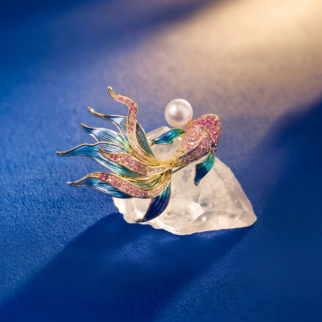 Aiko Tanaka Nishiki no Yume koi fish brooch with blue enamel fins and a pearl resting on a crystal over blue fabric