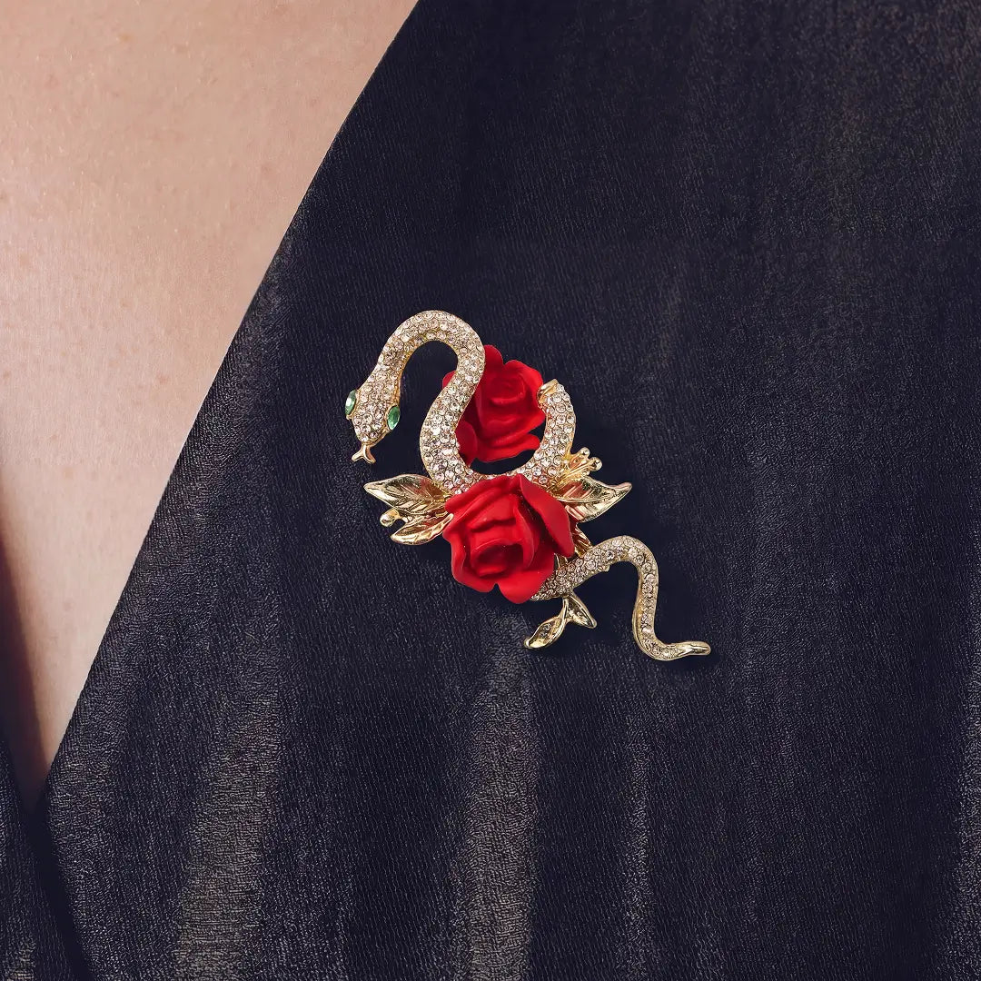 Aiko Tanaka Hebi no Chigiri brooch, a gold crystal snake wrapped around red roses, worn on a black V-neck top