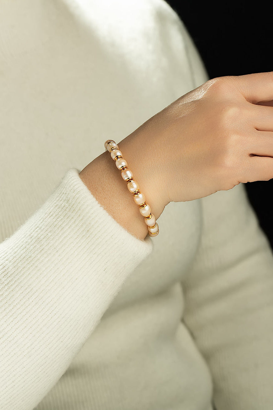 Wrist in a cream knit sweater wearing the Aiko Tanaka Hinata white pearl bracelet with gold bead spacers