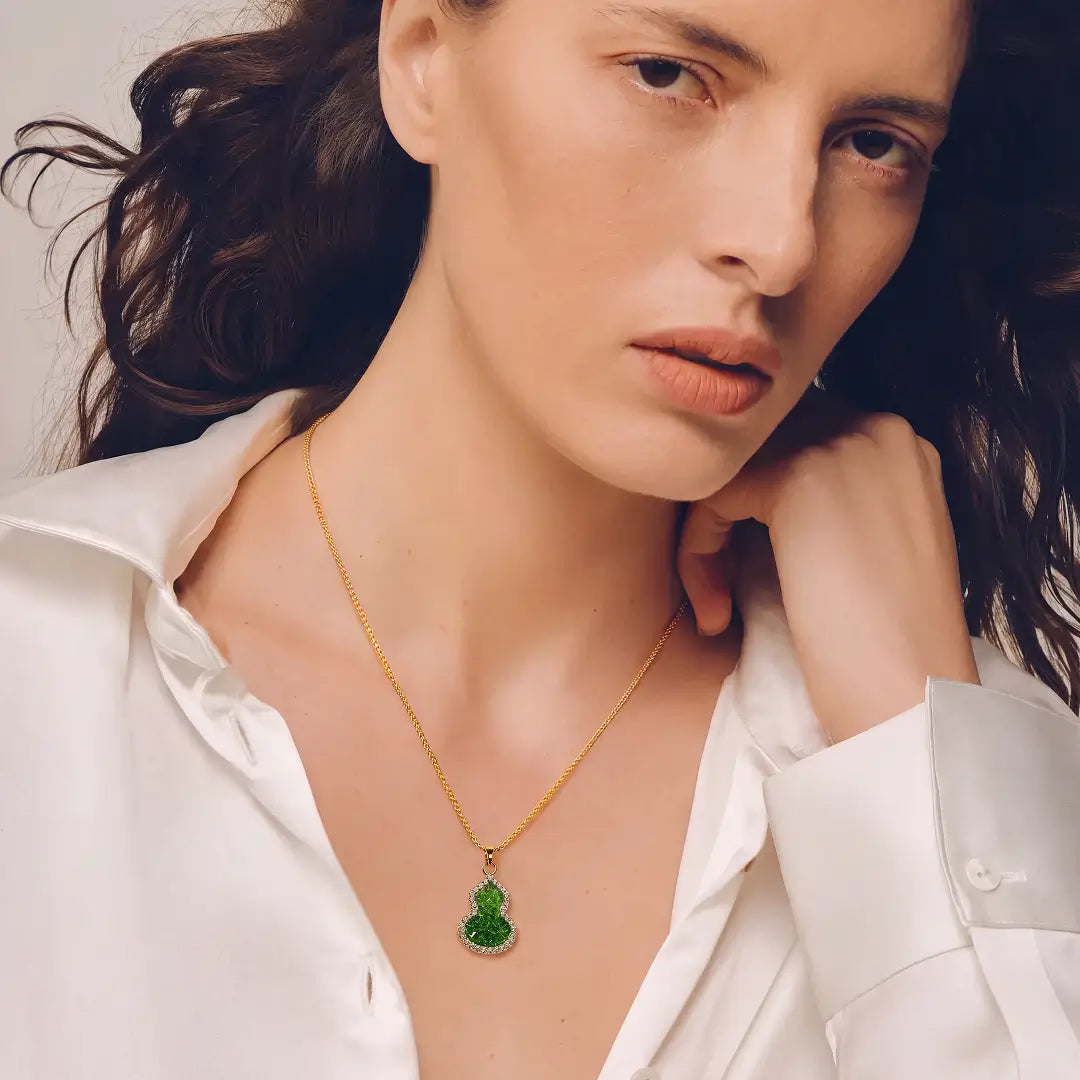 Aiko Tanaka Hisago necklace, a green gourd pendant on a gold chain, worn by a model in an open white shirt