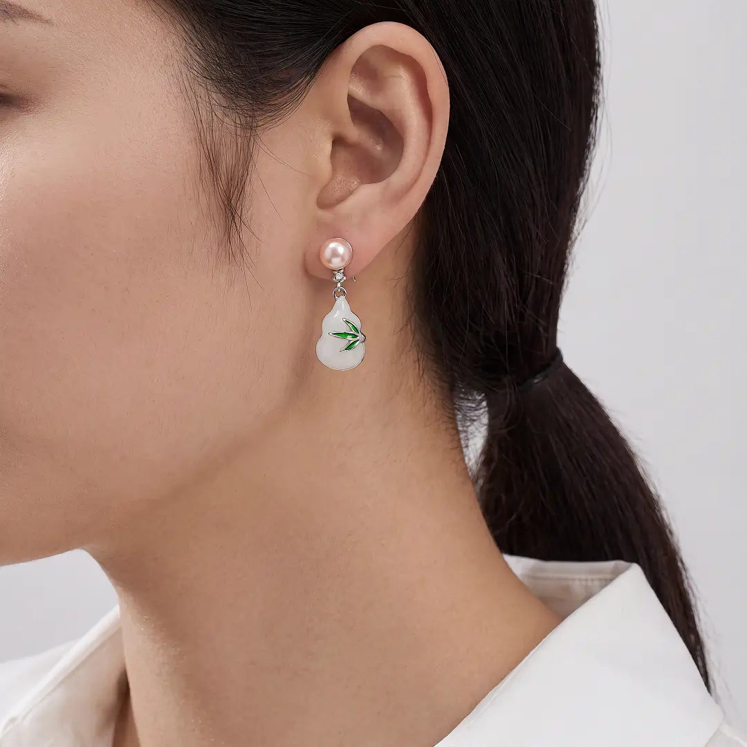 Aiko Tanaka Hisui no Mi earrings worn on the ear, a white gourd drop with a green leaf below a pearl stud