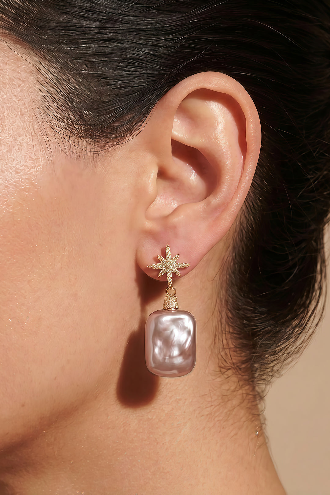 Ear wearing the Aiko Tanaka Hoshi no Kakera gold star earring with a rectangular lustrous baroque pearl drop