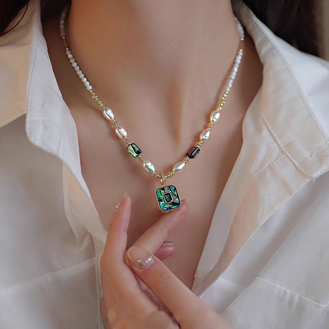 Woman in an open white shirt wearing the Aiko Tanaka Kai no Hoseki pearl necklace with a square abalone pendant