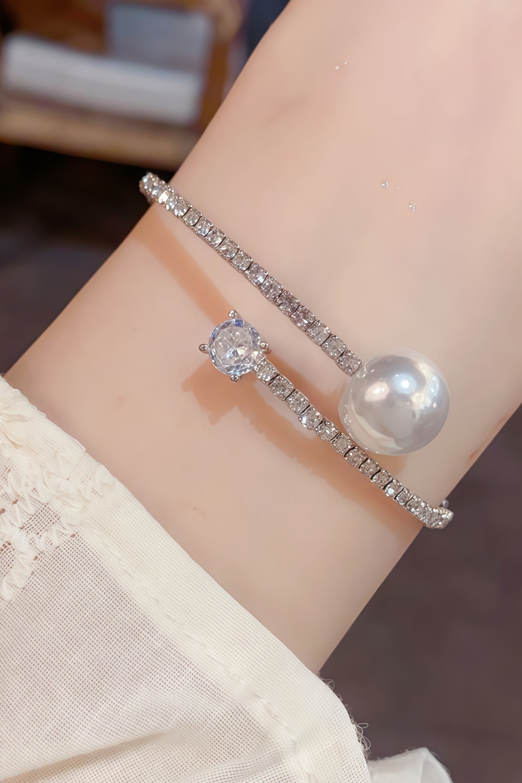 Wrist wearing the Aiko Tanaka Kinko no Wa silver crystal wrap bracelet with a large pearl and a round clear stone