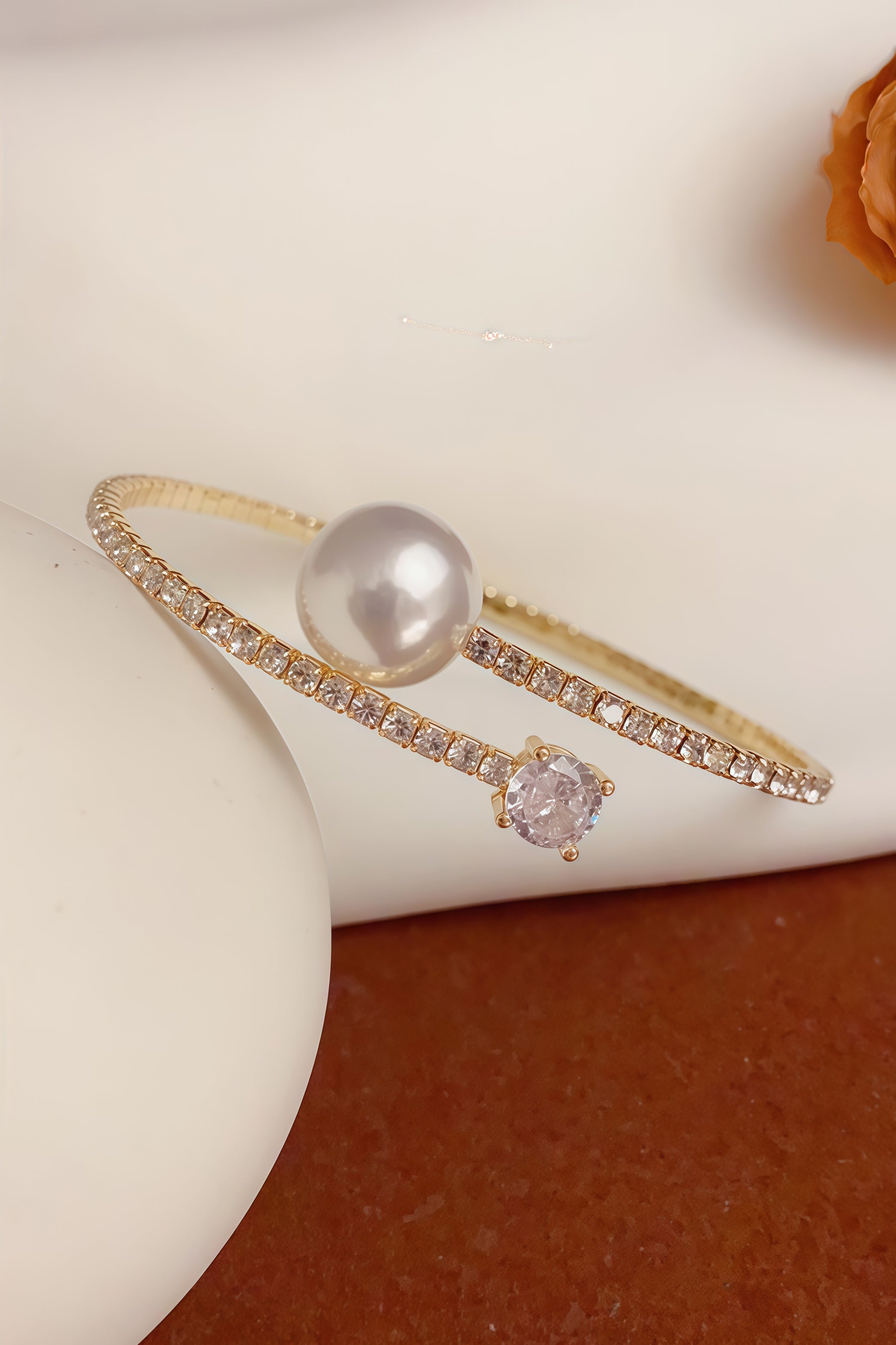 Aiko Tanaka Kinko no Wa gold crystal wrap bracelet with a pearl and pink stone, styled on a cream form and rust cloth