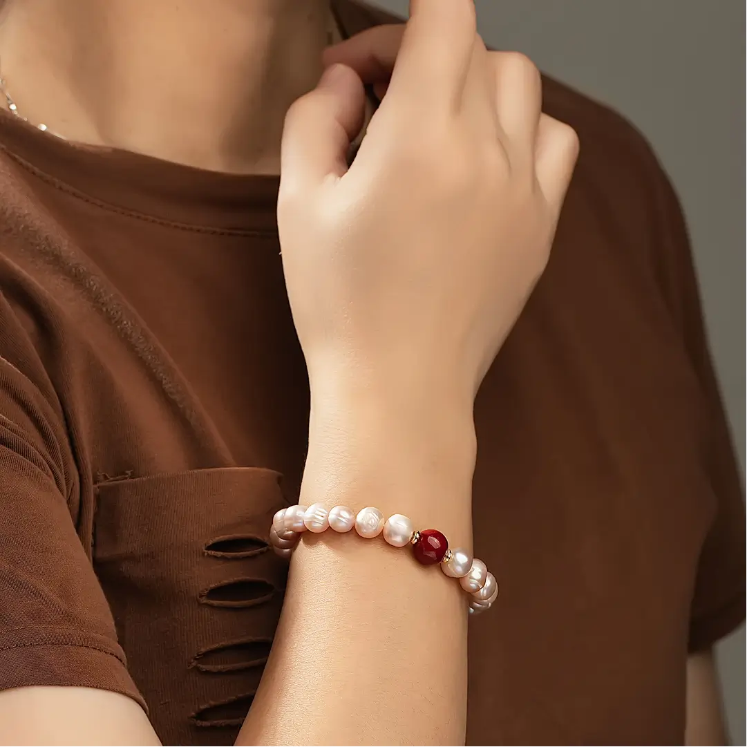 Aiko Tanaka Kurenai bracelet, pink freshwater pearls with a red bead, worn on the wrist with a brown top
