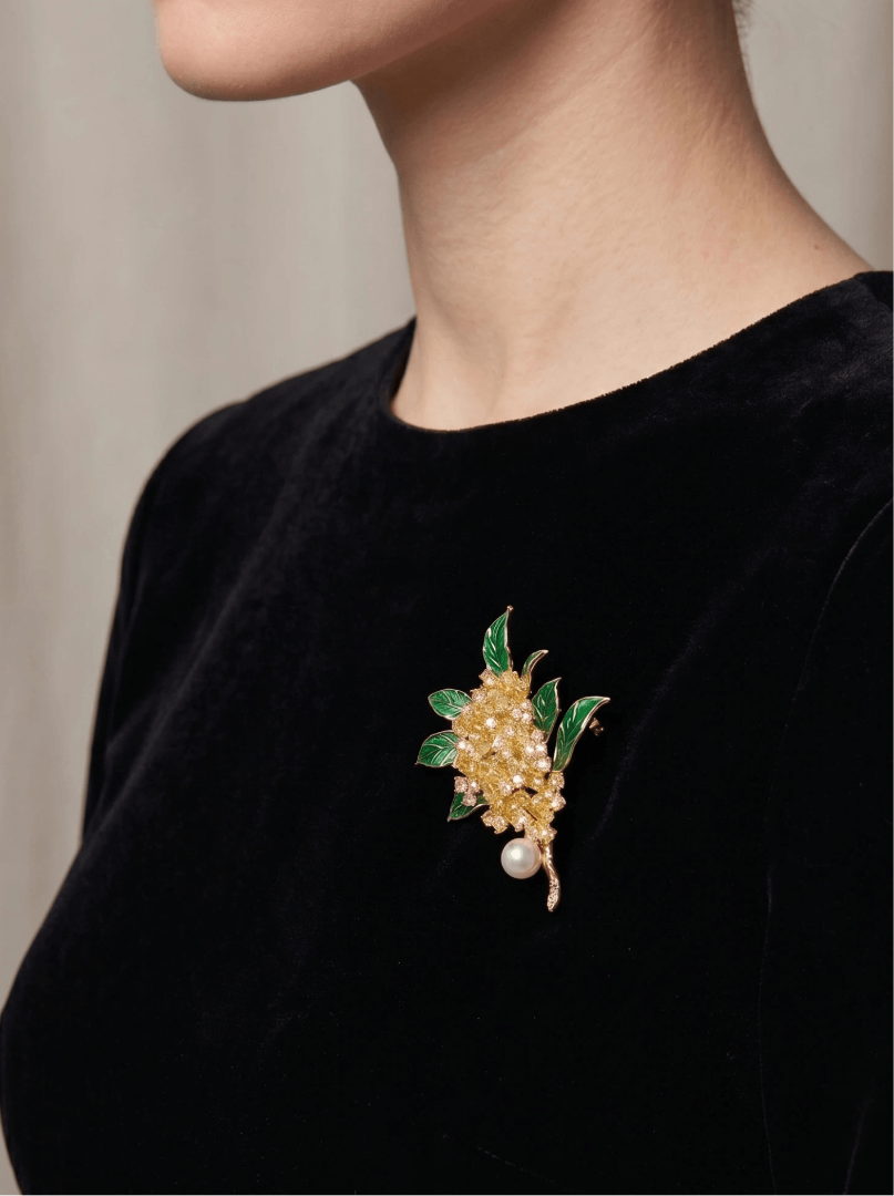 Woman in a black velvet top wearing the Aiko Tanaka Midori no Nagare gold flower and green leaf pearl brooch