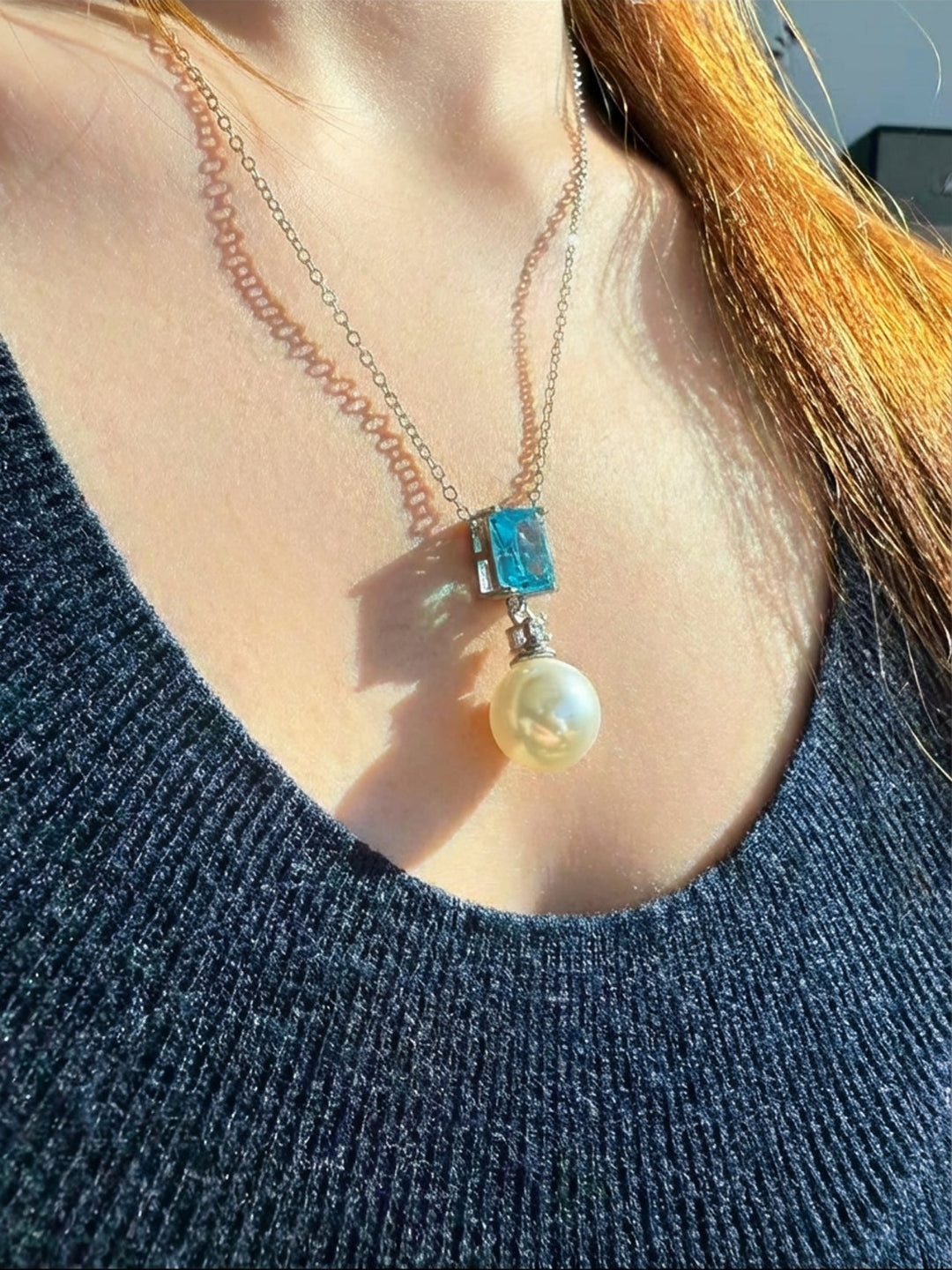 Aiko Tanaka Mizu Fracture pearl pendant necklace with an aqua cut stone on a fine chain, worn with a navy scoop neckline