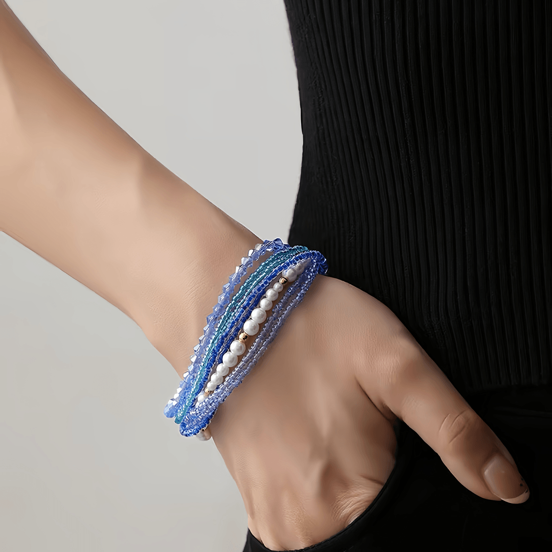 Aiko Tanaka Nami bracelet, layered blue bead and pearl strands, worn on the wrist against a black dress