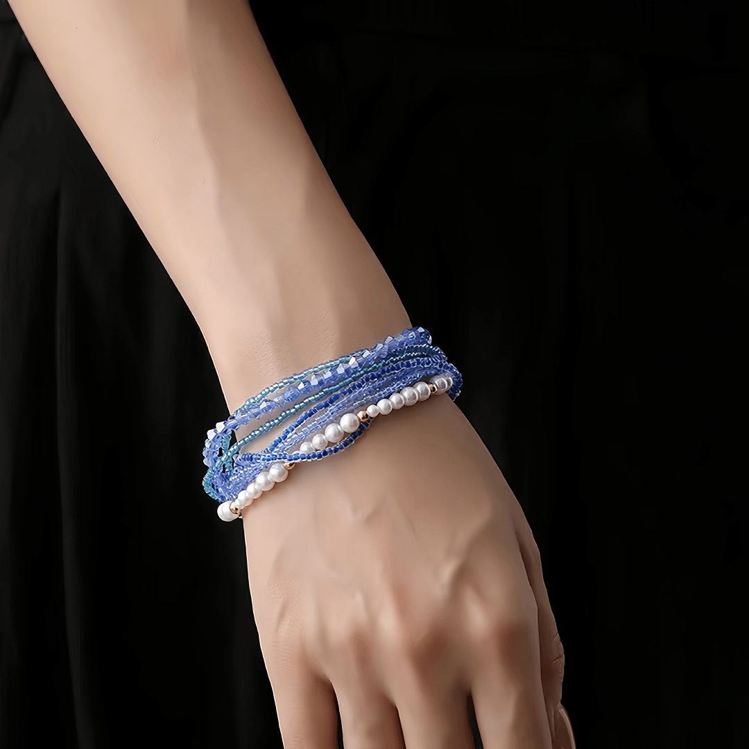 Aiko Tanaka Nami bracelet, wrapped strands of blue crystal beads and white pearls, worn on a wrist in black