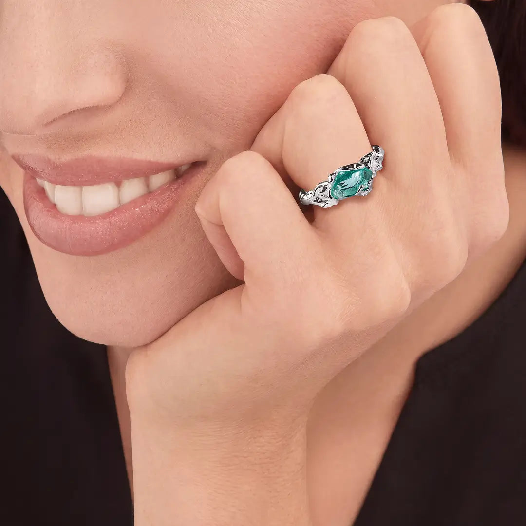 Aiko Tanaka Nami no Suisei ring, a silver band with a teal stone, worn by a smiling model with hand at her cheek