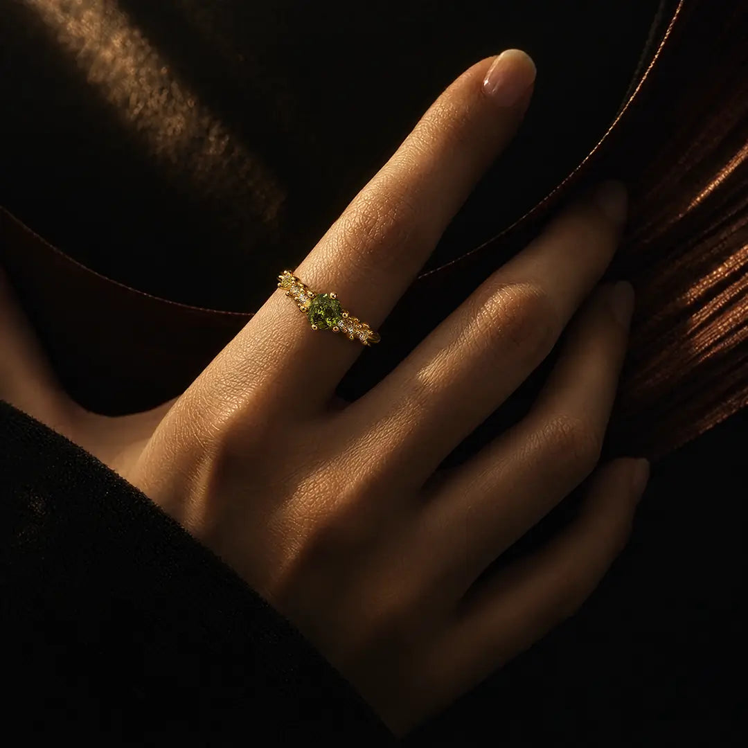 Aiko Tanaka Rensei ring, a slim gold band with a green stone, worn on the finger in warm dramatic light