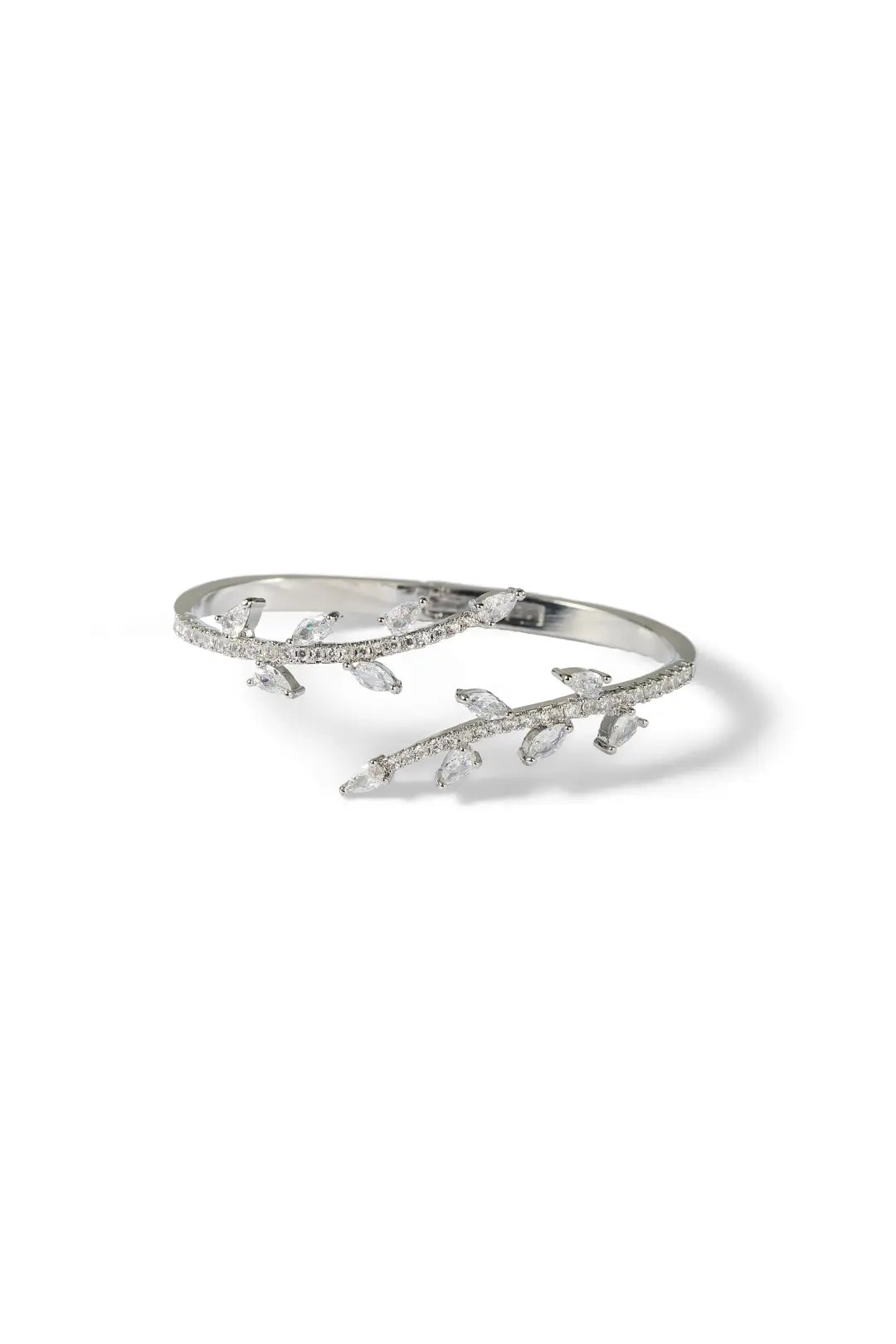 Aiko Tanaka Rinne bracelet, a silver cuff with crystal-set leaves along a branch, angled view on a white background