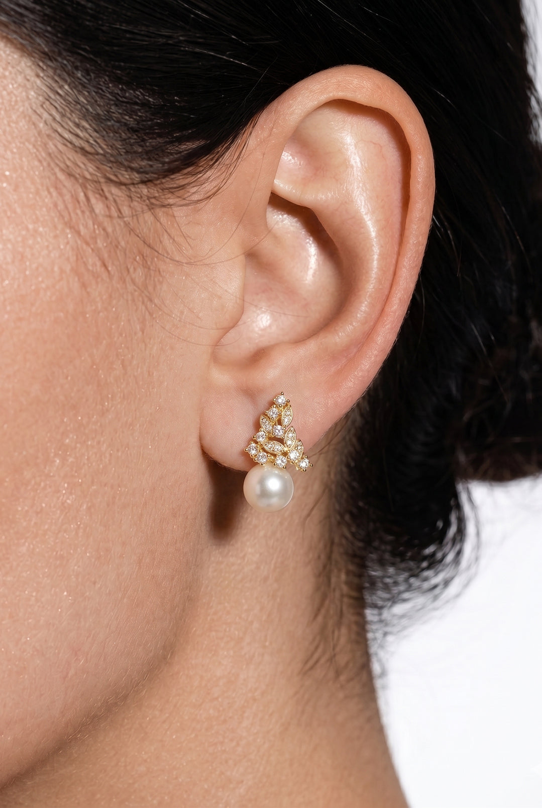 Close-up of an ear wearing the Aiko Tanaka Ritsu no Hikari gold crystal cluster earring with a small white pearl drop