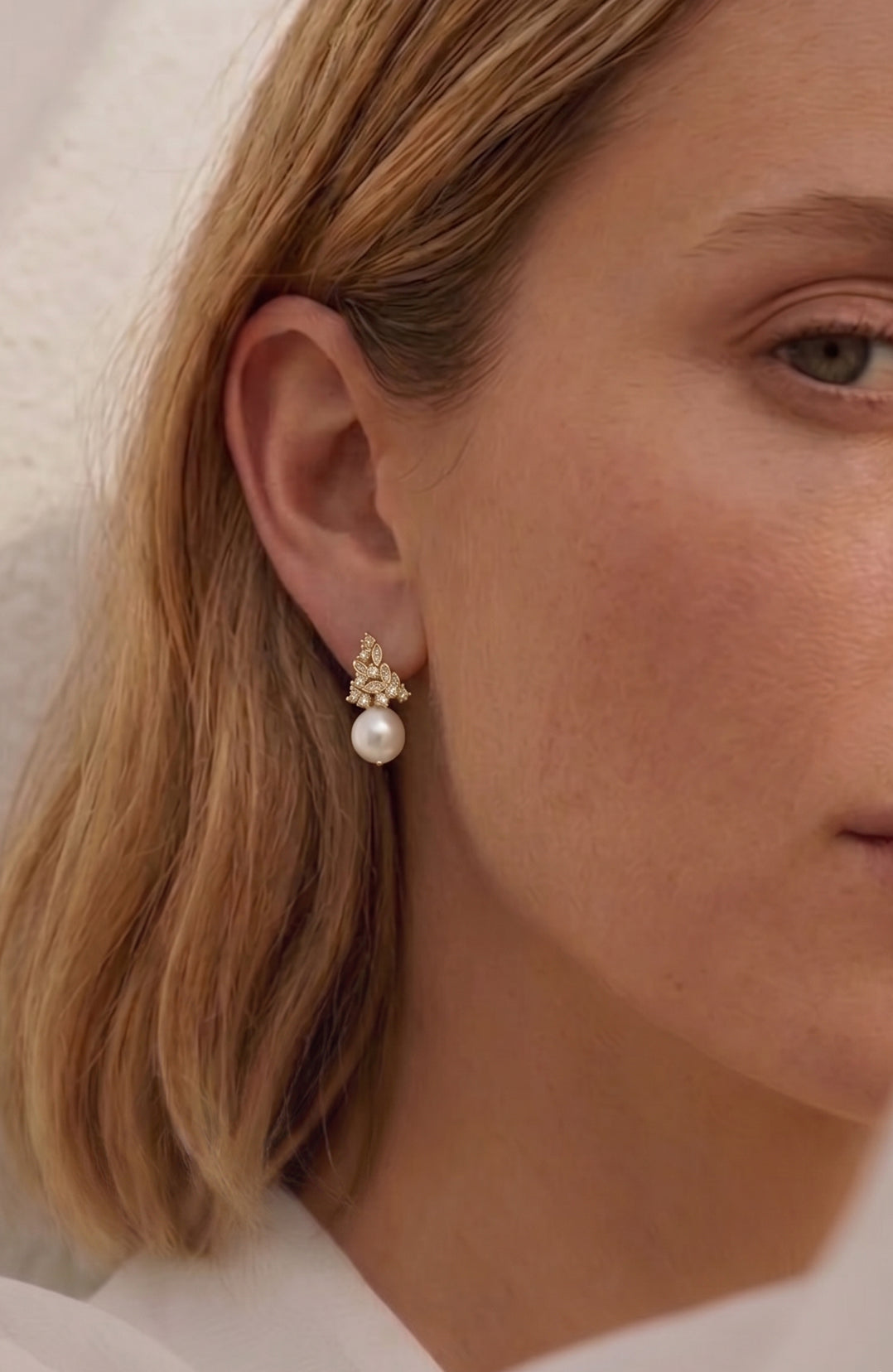 Woman with blonde hair wearing the Aiko Tanaka Ritsu no Hikari pearl and gold crystal earring, shown in profile