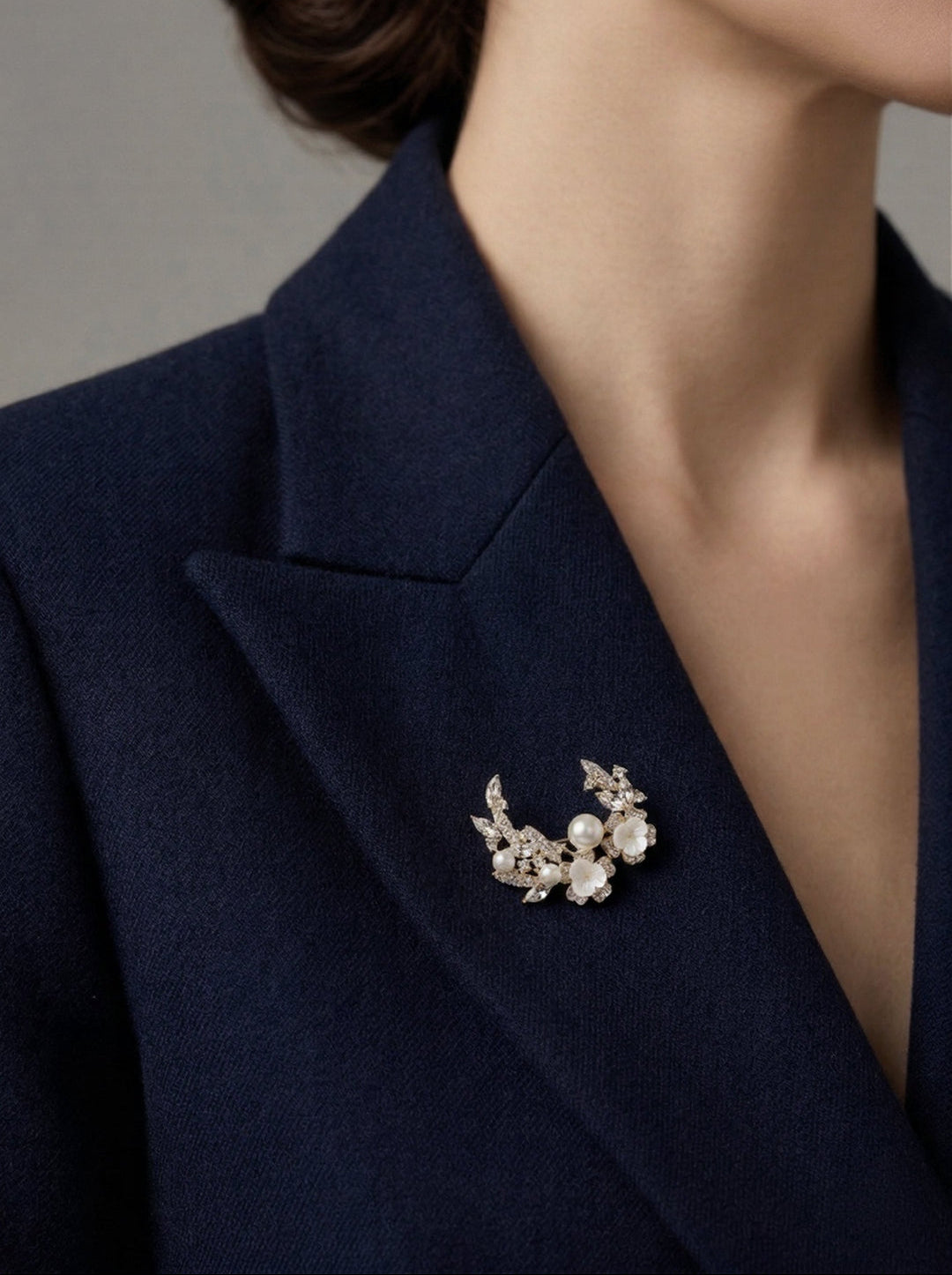 Woman in a navy blazer wearing the Aiko Tanaka Shiro no Kage crescent pearl and flower brooch on her lapel