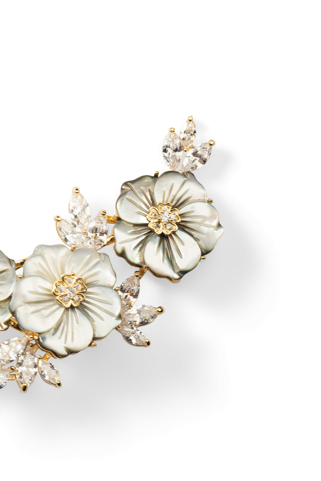 Close angled view of the Aiko Tanaka Shirohana no Uta mother-of-pearl blossom brooch with crystal buds, on white