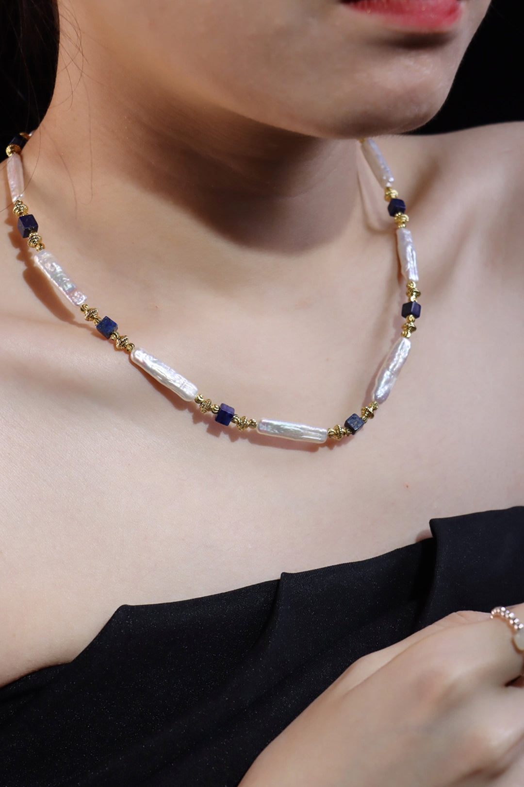 Woman in a black off-shoulder top wearing the Aiko Tanaka Shizuku no Kage stick pearl and navy bead necklace