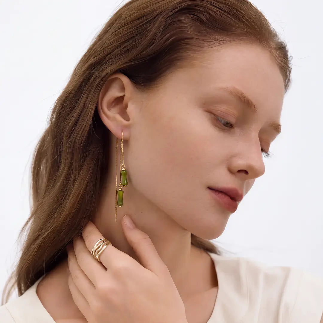 Aiko Tanaka Take no Kaze earrings, gold threaders with green bamboo segment drops, worn by a red-haired model