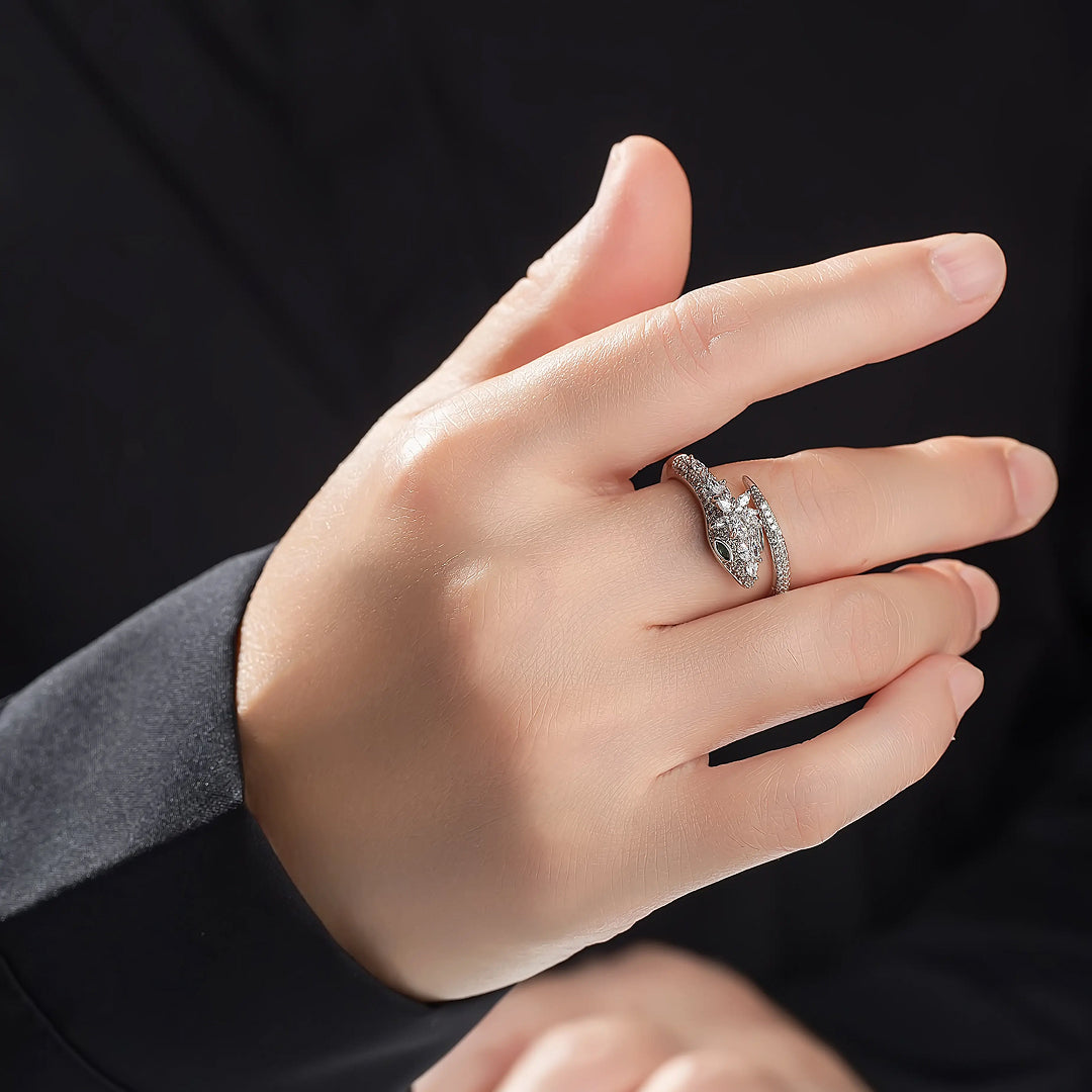 Hand in a grey sleeve wearing the Aiko Tanaka Tokage no Mori silver lizard ring against a black background