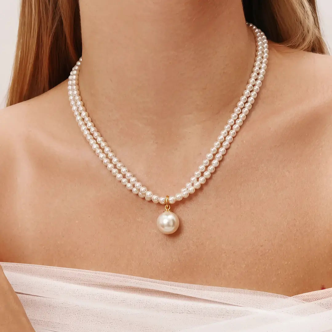 Aiko Tanaka Tsukishiro necklace, a two-strand seed pearl necklace with a round pearl pendant, worn off-shoulder