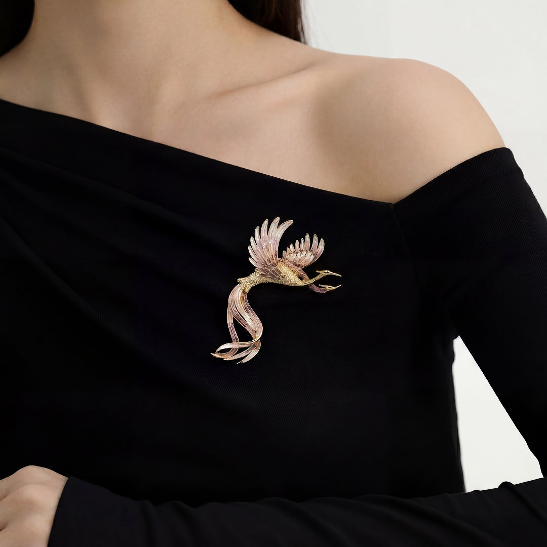 Woman in a black off-shoulder top wearing the Aiko Tanaka Tsuru no Korin gold and pink enamel crane brooch
