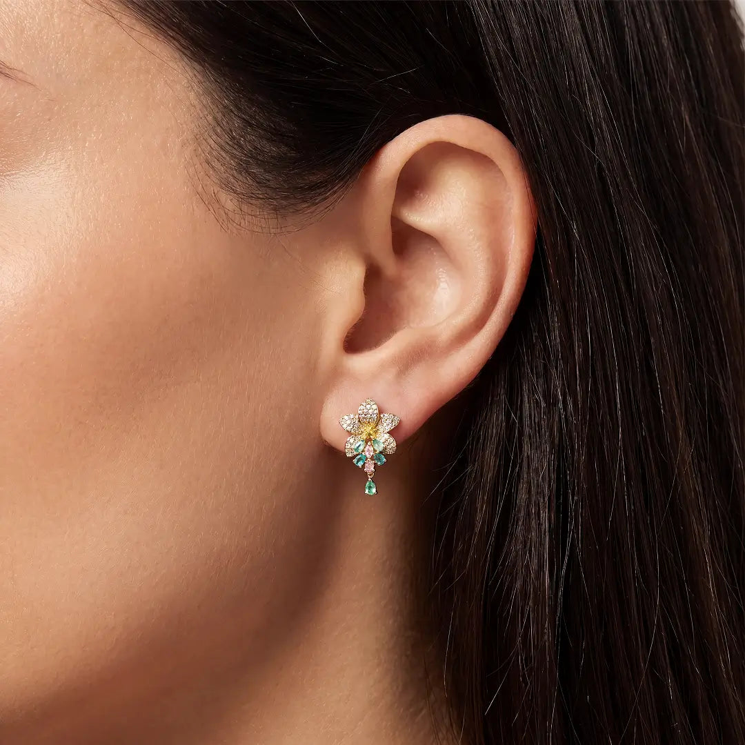 Close-up of an ear wearing the Aiko Tanaka Wakana flower earring with green and pink stone drops