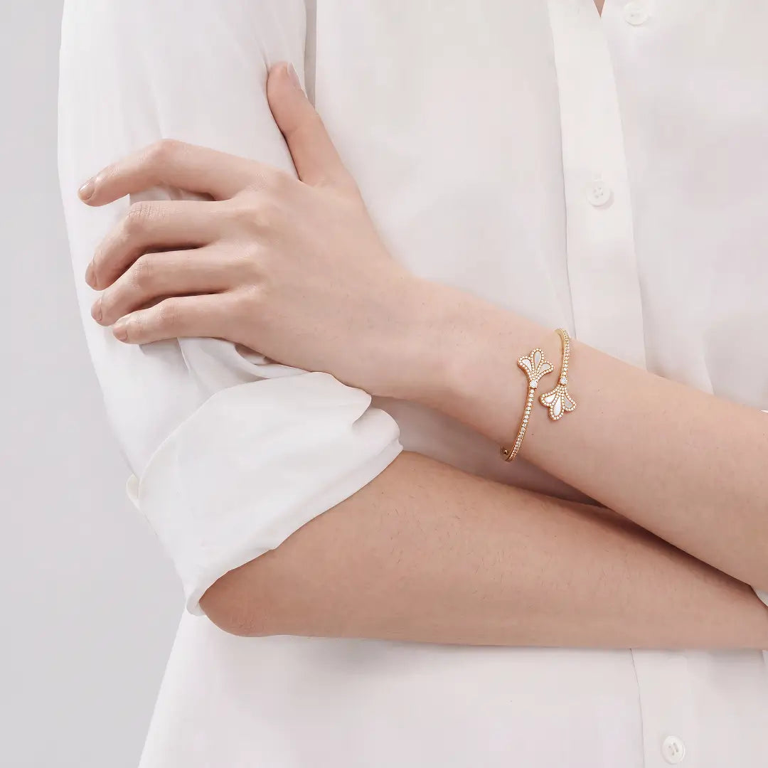 Aiko Tanaka Yohaku bracelet, a gold cuff with ginkgo leaf ends, worn on the wrist with a white shirt rolled at the sleeve