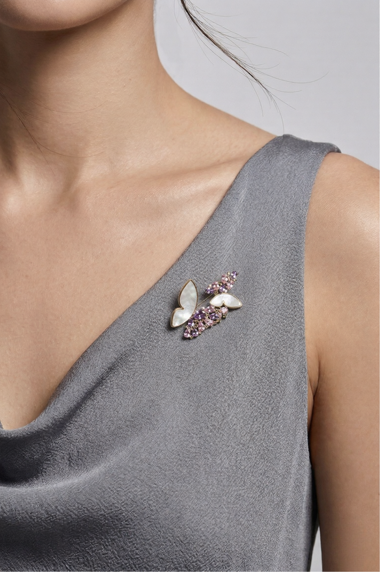 Woman in a grey draped top wearing the Aiko Tanaka Yume no Tsubasa mother-of-pearl and purple crystal butterfly brooch
